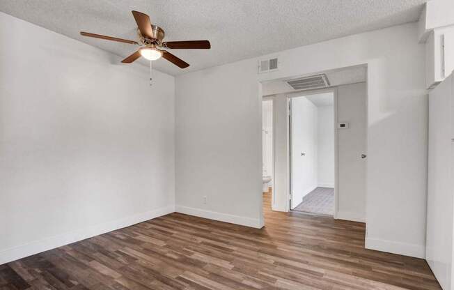 A room with a ceiling fan and wooden flooring.