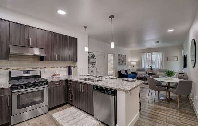 Modern open kitchen with stainless steel appliances, a marble countertop, and sleek cabinetry.