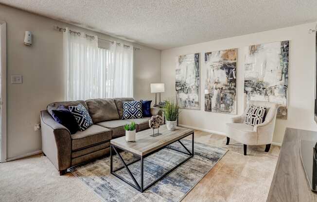 A living room with a couch, a chair, a coffee table, and pictures on the wall.