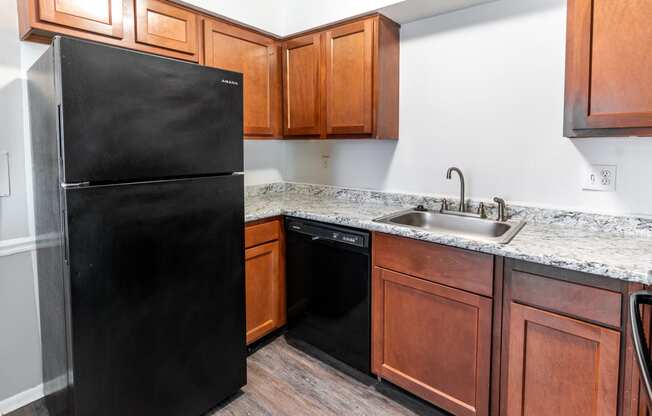 a kitchen with a black refrigerator and wooden cabinets