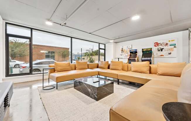 A modern living room with a large sectional sofa and a coffee table in front of a large window.