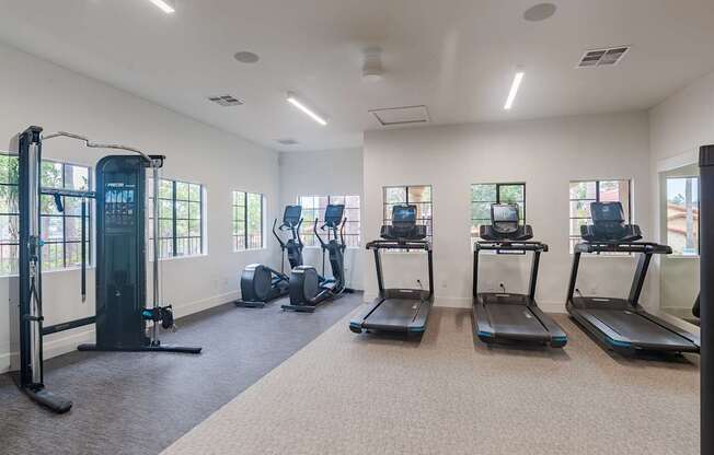 A gym with treadmills, elliptical machines, and a weight machine.
