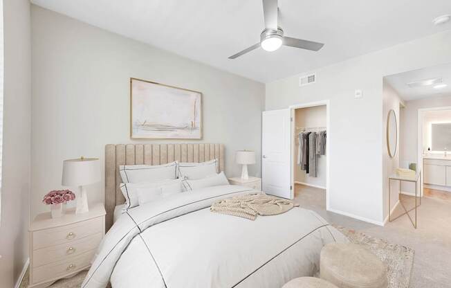 A bedroom with a large bed, a ceiling fan, and a painting on the wall.