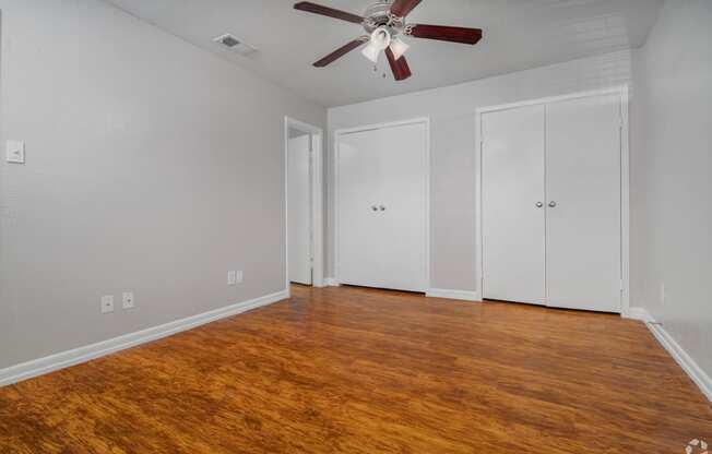 an empty living room with wood floors and a ceiling fan