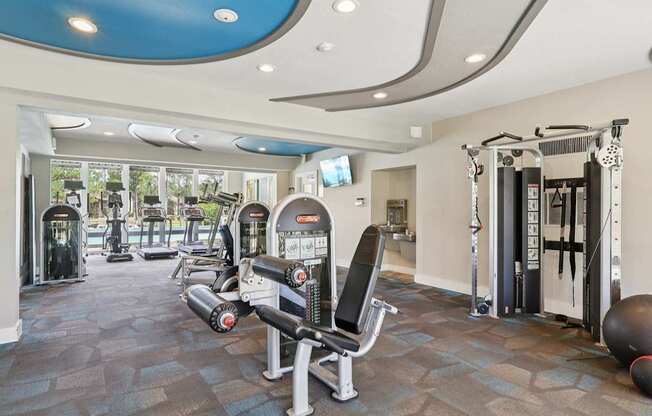 A gym with a variety of equipment including a rowing machine, a leg press machine, a weight bench, and a medicine ball.