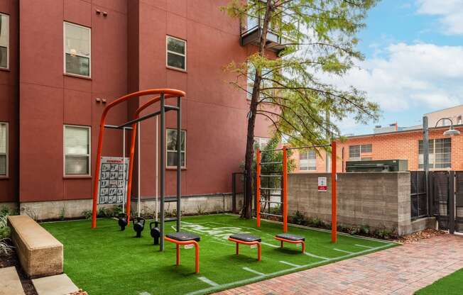 a playground with grass and benches in front of a brick building