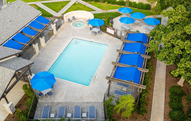 an aerial view of a swimming pool with blue umbrellas