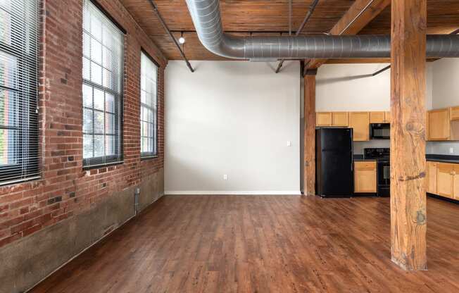 an empty living room with a brick wall and wood floors