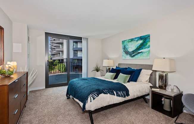 A bedroom with a bed, nightstand, and a painting on the wall.