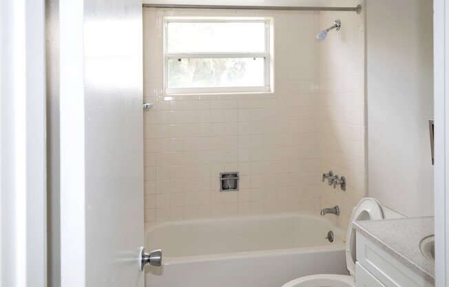 A white bathroom with a tub, toilet, and sink.