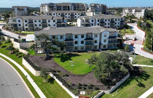 an aerial view of an apartment complex with a green lawn and a road
