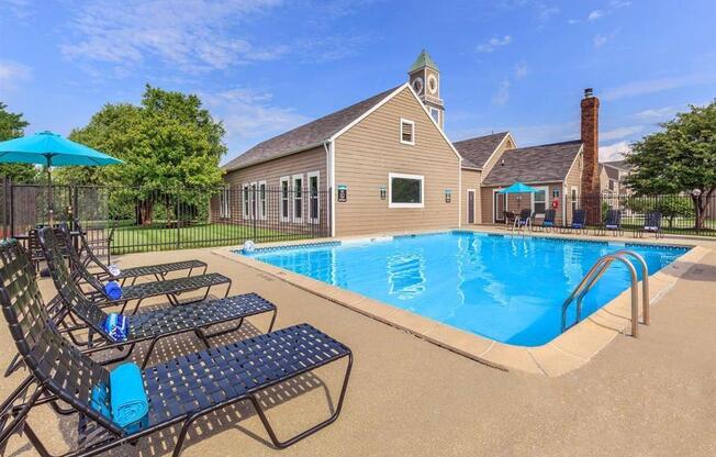 a pool with chairs and a house in the background
