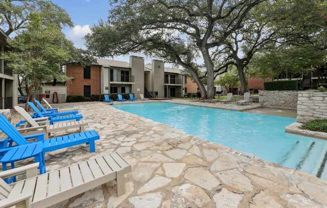 A pool surrounded by blue and white lounge chairs at Westdale Pointe in Austin, TX