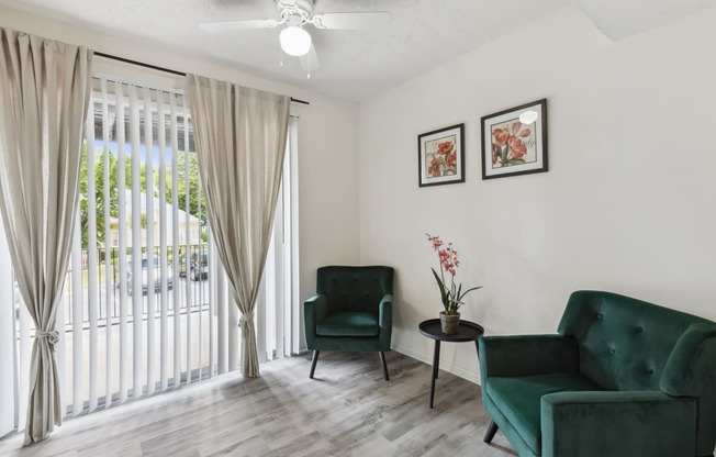 a living room with two green chairs and a ceiling fan