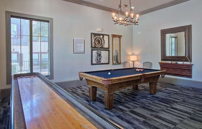 A pool table in a room with a chandelier and a mirror.