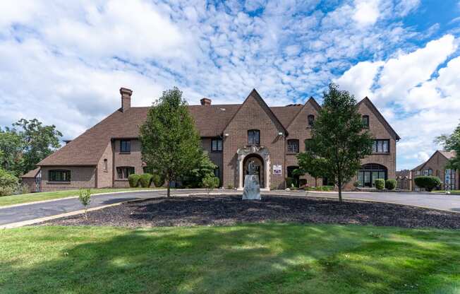 a large brick house with a statue in front of it