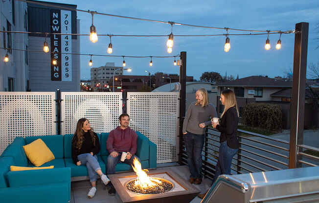 a group of people sitting around a fire pit on a rooftop patio at The Landing at 1001 NP, Fargo, ND 58102