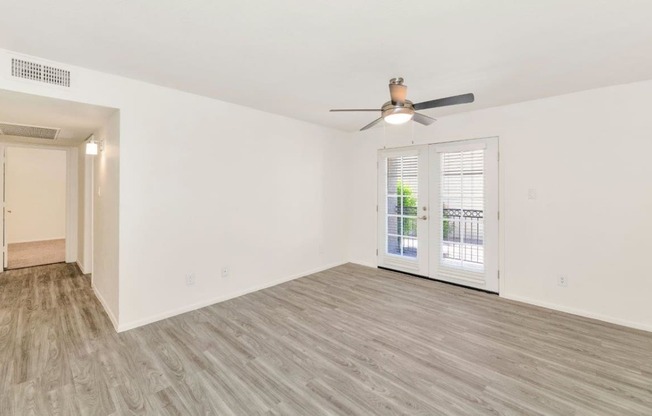 an empty living room with a ceiling fan