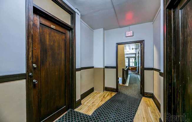 A hallway with a wooden door on the left and a black and white checkered floor.