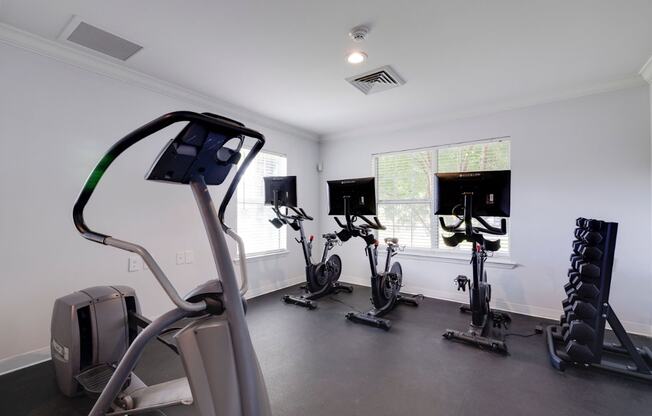 A gym with a treadmill, exercise bike, and weights.