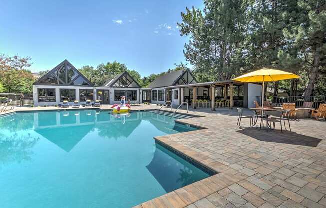 A large outdoor swimming pool with a yellow umbrella and a house in the background.