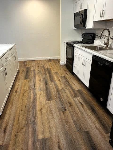 a kitchen with white cabinets and a wooden floor