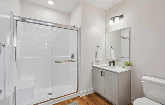 A white bathroom with a walk-in shower, toilet, and sink.