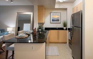 A modern kitchen with a black countertop and stainless steel appliances.