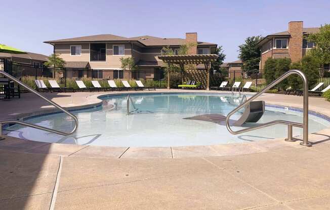 a swimming pool with chairs around it and a building in the background