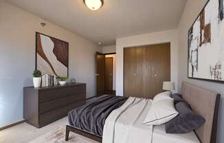 a bedroom with a bed and a dresser and a door to a bathroom. Fargo, ND Eagle Run Apartments