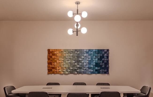 a conference room with a table and chairs and a painting on the wall