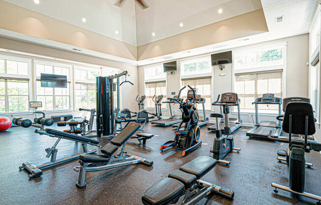 a spacious gym with cardio equipment and windows