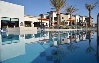 A pool in front of a building with palm trees.