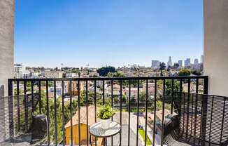 a balcony with two chairs and a table and a view of the city