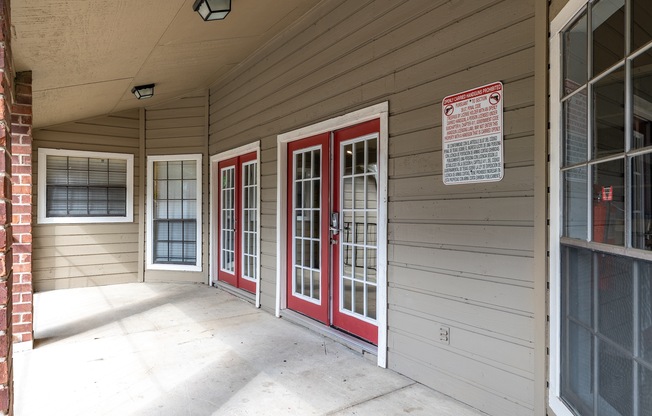 A porch with red doors and a sign on the wall.
