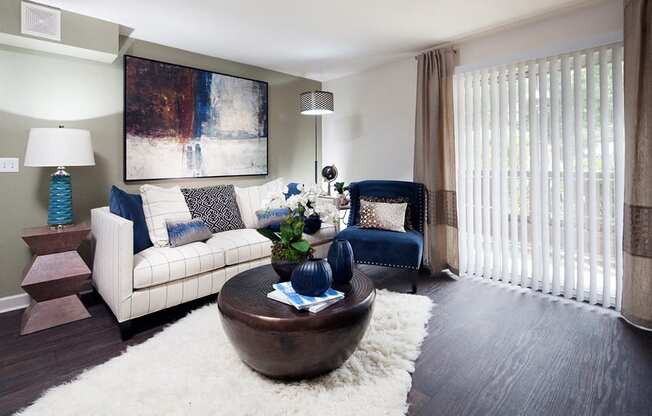 Ardenne Apartments model apartments with a white couch, blue chair and hardwood-style floor