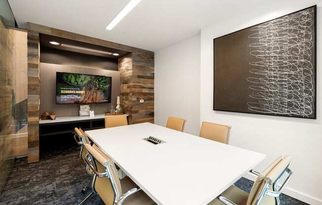 a conference room with a white table and chairs and a tv