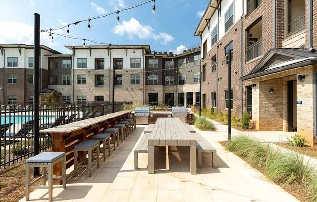 an outdoor patio with tables and benches at a building with a pool