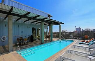 the pool on the rooftop of a building with a city in the background