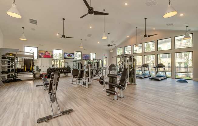 a gym with weights and cardio equipment and windows at Legacy at Cibolo, Boerne, TX