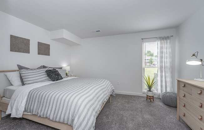 Bedroom with cozy bed and window at Bloomfield Apartments, Dayton