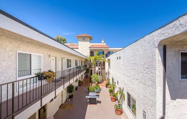 a courtyard between two buildings with benches and potted plants