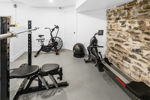 a gym with exercise equipment and a stone wall