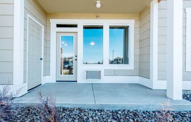 the front of a house with a white door and windows with a blue sky in the background