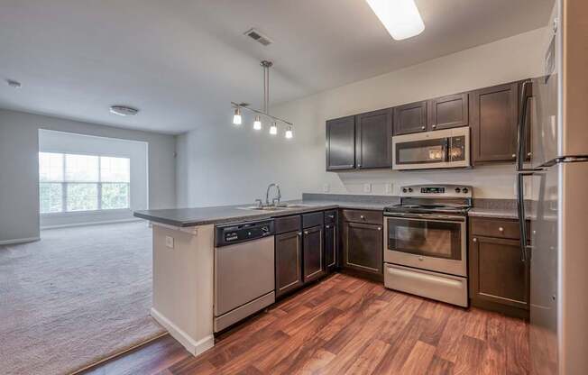 A modern kitchen with dark brown cabinets and stainless steel appliances.