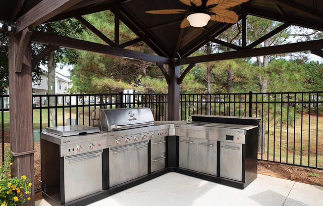 A BBQ grill set up under a wooden pavilion.