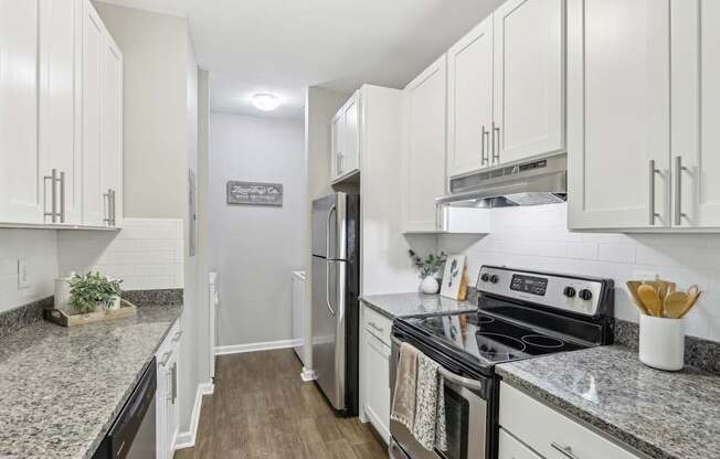 A kitchen with white cabinets and a granite countertop.