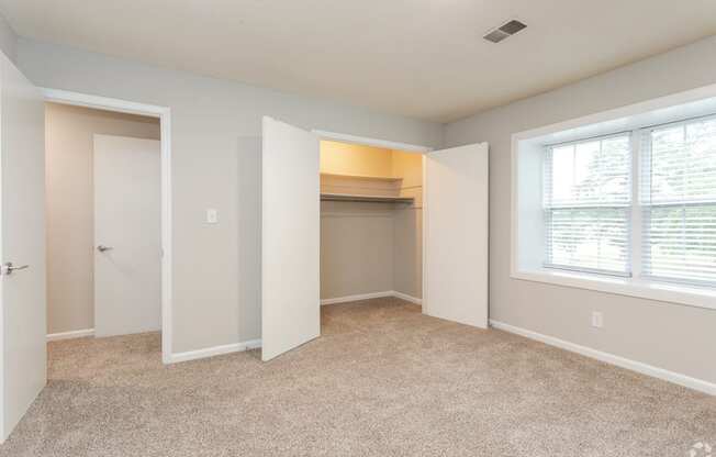 an empty bedroom with a closet and a window