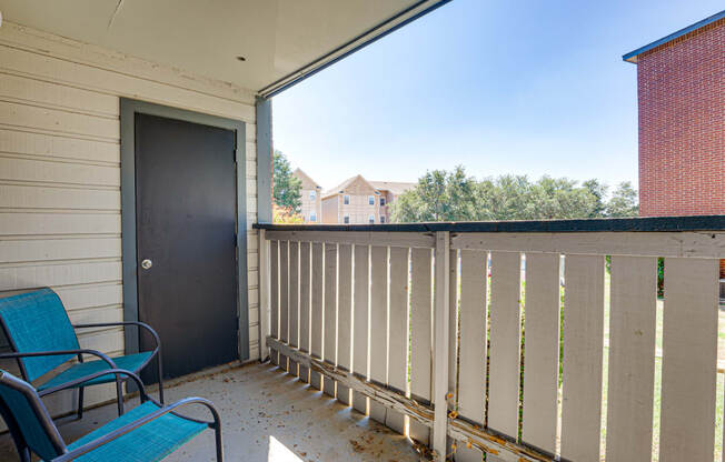 the deck has a black door and two blue chairs on it