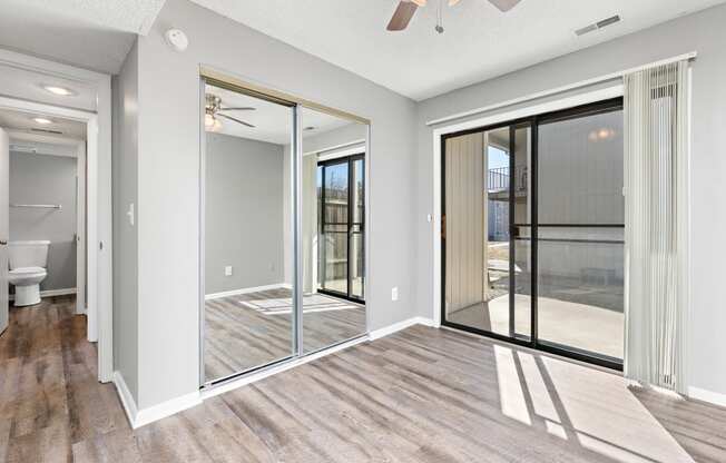 Living room with large patio door and closet with mirror doors at Eddingham in Lawrence, KS